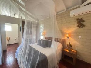 une chambre avec un lit avec moustiquaire dans l'établissement Indigo Palmes, à Sainte-Rose