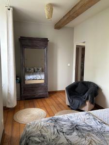 a bedroom with a bed and a mirror and a chair at La maison du bonheur 17 in Marans