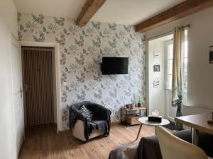 a living room with a chair and a tv on a wall at La maison du bonheur 17 in Marans