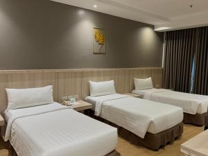 ein Hotelzimmer mit drei Betten in einem Zimmer in der Unterkunft Bajada Suites in Davao City