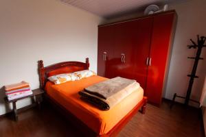 een slaapkamer met een oranje bed en een rode kast bij Casa Joseph in Gramado