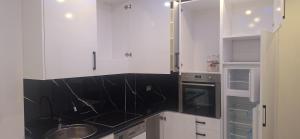 eine Küche mit weißen Schränken und schwarzen Arbeitsplatten in der Unterkunft Locker in Prizren