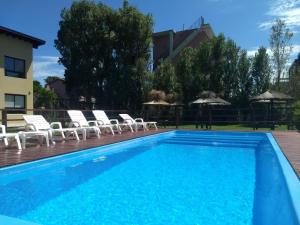 a pool with chairs and umbrellas on a deck at Los Curlis Dpto 2 Amb Las Gaviotas Mar Azul in Las Gaviotas