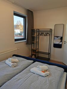 deux lits dans une chambre avec des serviettes dessus dans l'établissement Modernes Apartment mit Parkplatz und 24h Check-in, à Niederdorla