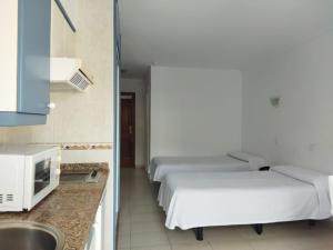 a row of beds in a room with a kitchen at Estudio con Piscina en Puerto de la Cruz in Puerto de la Cruz