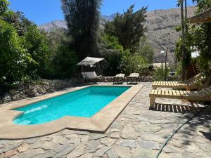 una piscina con dos sillas y una mesa en Cabaña hostal Ema, en Pisco Elqui