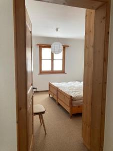 a bedroom with a bed and a chair and a window at Chesa Muntanaia in Pontresina +8 photos