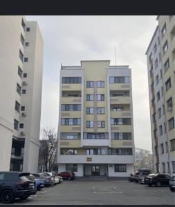 a tall building with cars parked in a parking lot at Sunset view in Craiova