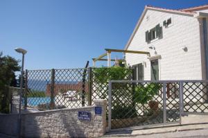 einen Zaun vor einem weißen Gebäude mit einem Haus in der Unterkunft Ferienhaus für 8 Personen ca 110 qm in Sumartin, Dalmatien Mitteldalmatien in Sumartin