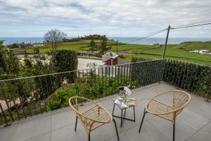 ein Balkon mit zwei Stühlen und einem Tisch mit Aussicht in der Unterkunft Ferienhaus für 2 Personen ca 50 qm in Algarvia, Azoren Sao Miguel in Algarvia