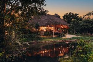 a hut with a thatched roof next to a river at Casa Caona in El Valle