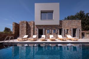 a villa with a swimming pool and lounge chairs at Haus In Agios Nikolaos Mit Außergewöhnlicher Aussicht in Agios Nikolaos