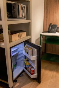 メデジンにあるSloh Hotel & Bar Manila Medellinの電子レンジの隣に開くドア付きの冷蔵庫