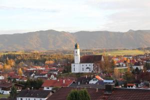 une ville avec une église et des montagnes en arrière-plan dans l'établissement Morgensonne, à Lechbruck am See