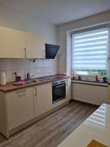 a kitchen with white cabinets and a sink and a window at Zentrale, Liebevoll Eingerichtete Ferienwohnung in Monheim