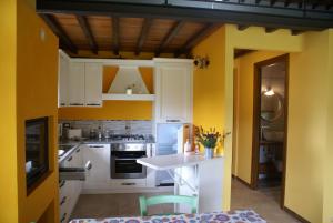 une cuisine avec des murs jaunes, des armoires blanches et une table dans l'établissement Sunset Barga Toskana Kürzlich Renoviert, à Barga 16 autres photos