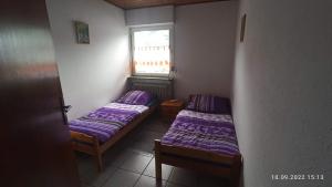 2 posti letto in una piccola camera con lenzuola viola di Albferienhaus Schaette a Giengen an der Brenz Altre 11 foto