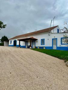 ein weißes und blaues Haus mit Kieseinfahrt in der Unterkunft Casal do Pequeno in Alcobaça