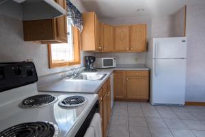a kitchen with a sink and a white refrigerator at Adirondack Retreat Inn & Suites in Lake George
