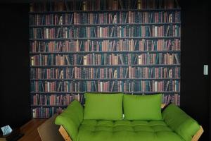 a green couch in front of a wall of books at Santari in Shintoku
