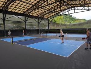 a group of people playing tennis on a tennis court at Finca Cacao in Pavones