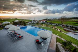 eine Luftansicht auf einen Pool mit Sonnenschirmen und Stühlen in der Unterkunft Ferienhaus für 4 Personen ca 120 qm in Algarvia, Azoren Sao Miguel in Algarvia