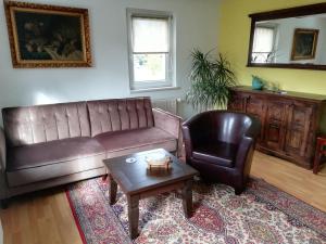 ein Wohnzimmer mit einem Ledersofa und einem Stuhl in der Unterkunft Kleine Ferienwohnung in Freital bei Dresden in Freital
