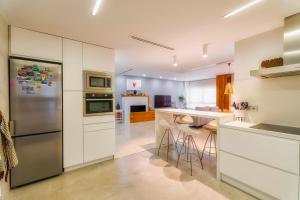 une cuisine avec des armoires blanches et un réfrigérateur en acier inoxydable dans l'établissement centro / internet / parking / aire acondicionado, à Elche