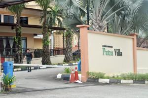a man walking in front of a building with palm trees at Putra Villa Short Stay Apartment KL in Kuala Lumpur