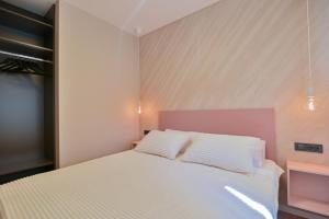 a bedroom with a white bed with a pink headboard at Noir Design Wohnung in Trogir