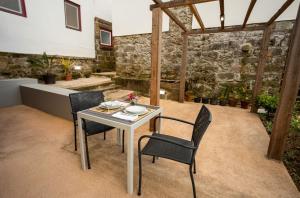 eine Terrasse mit einem Tisch, Stühlen und einer Steinmauer in der Unterkunft Ferienhaus für 2 Personen ca 50 qm in Algarvia, Azoren Sao Miguel in Algarvia