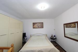 a white bedroom with a bed and a mirror at Котедж "Красний Краєвид" in Yaremche