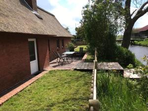 une arrière-cour avec une table de pique-nique et une maison dans l'établissement Gemütliches Reetdachhaus In Schleswig Holstein, à Neuendorf-Sachsenbande