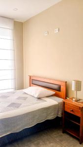 a bedroom with a bed and a table with a lamp at Apartamento JATUN MAMA in Chancay