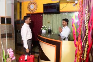 two men standing at a bar in a room at Royal Residency in Pedappai