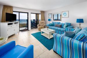 a living room with blue couches and a television at Surf Dweller 312 Large gulf front in Fort Walton Beach