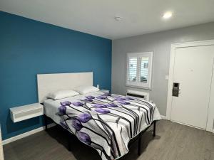 ein Schlafzimmer mit einem Bett mit einer blauen Wand in der Unterkunft Angel's Motel near Anaheim in Orange