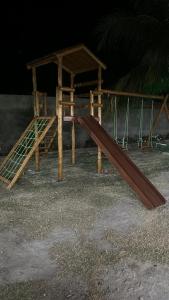 a wooden playground with a slide and a wooden roof at Chácara Santa Terezinha in Quixeramobim