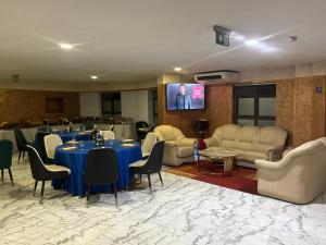 Una sala con mesas y sillas y un televisor de pantalla plana. en FOPROLUX Palace, en Douala