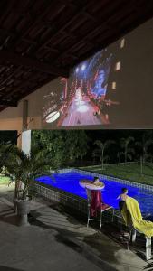 a large screen with a movie on top of a pool at Chácara Santa Terezinha in Quixeramobim