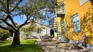 une maison jaune avec une table et un arbre dans l'établissement Stylish vacation home - close to sea and nature, à Hejls