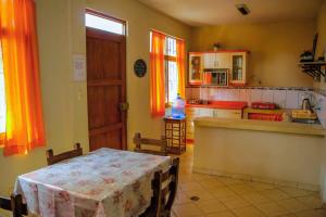 una cucina con tavolo e una cucina con tende arancioni di Lupita House a Máncora