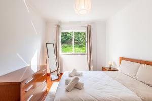 ein weißes Schlafzimmer mit einem Bett und einem Fenster in der Unterkunft Brisa do Caniço in Caniço