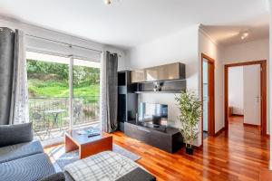 ein Wohnzimmer mit Sofa und Fernseher in der Unterkunft Brisa do Caniço in Caniço