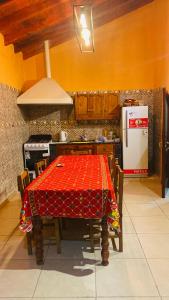 eine Küche mit einem roten Tisch mit Stühlen und einem Kühlschrank in der Unterkunft El kincho in Humahuaca