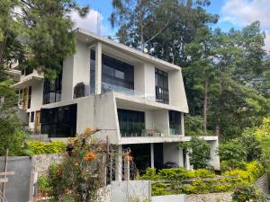 a white house with trees in front of it at Casa Verapaz in Santa Catarina Palopó