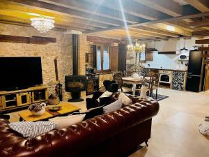 a living room with a brown leather couch and a television at BocallenaRural LASTRAS DE CUELLAR in Lastras de Cuéllar
