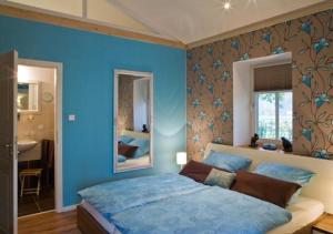 - une chambre bleue avec un lit et un miroir dans l'établissement Apartment Teichblick Mit Eigener Terrasse, à Klein Meckelsen