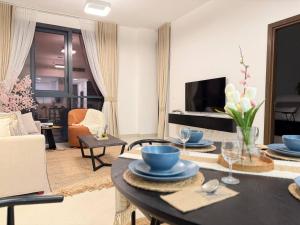 a living room with a table and a tv at ASHRI HH | Elegant 1BR in Ajmal Makan | Beachfront in Al Ḩamrīyah