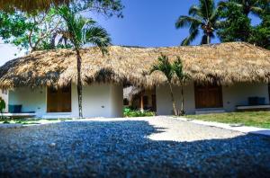 una casa con techo de paja y palmeras en Nomadas 5 bdrs villa with private pool 2nd line to beach, en Las Terrenas